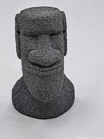 Front view of the miniature Moai statue showing facial features and textured surface.