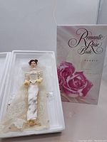 Romantic Rose Bride Barbie doll in foam packaging alongside its original box featuring rose design and limited edition labeling.