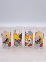 Four vintage 80s/90s drinking glasses with colorful fruit illustrations shown side by side.