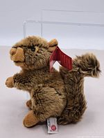 Side view of brown squirrel plush with bushy tail and tag.