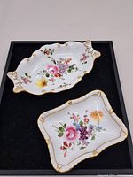 Top view showing two porcelain dishes with floral decorations and gold trim.