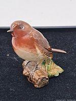 Angled front-left view of the porcelain robin figurine showing colors and details of the bird and base.