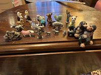 Photo showing a variety of small animal-themed knick knacks including birds, mammals, and more in varying materials such as wood, metal, ceramic, glass, and resin on wooden surface.
