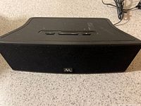 Front angle of black AR Bluetooth speaker showing top control buttons and logo on front grille.