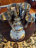 All pots and lids displayed together on a table, showing the set and stacking of triple boiler