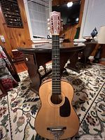 Front view of Des Laurier acoustic guitar with natural wood finish and pickguard.
