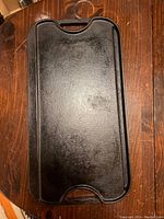 Top view of the Lodge cast iron griddle showing the flat smooth cooking surface with integrated handles on each end.