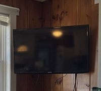 Samsung 40-inch LED TV mounted on wood-paneled wall showing front view with black screen and Samsung logo.