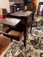 Side view of one brown antique solid wood nightstand showing open pull out drawer and extended pull out shelf, with visible wood grain and finish.