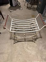 Wrought iron seat with scooped metal slat seat and wooden handled arm rests, viewed from above and front.