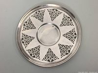 Top view of round pierced silver plate showing alternating solid and ornate pierced triangular segments