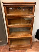 Front view showing four stacked sections with glass drop-down doors and rope molding