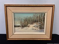 Full view of the framed oil painting showing the winter landscape scene on masonite, including the signature and frame condition.