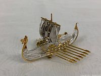 Side view of crystal Viking longship showing faceted hull, gold dragon head prow, mast, sail, and oars.