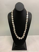 Full view of the 26 inch freshwater coin pearl necklace displayed on black mannequin bust.