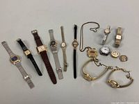 Full overview of all watches and necklaces shown together on white background to show lot contents.