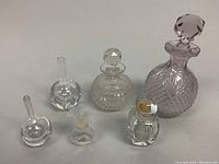 Group photo of six vintage crystal perfume bottles including two larger Orrefors with cut designs and four smaller clear bottles with stoppers