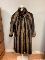 Full front view of the raccoon fur coat on a mannequin, showing length and striped fur pattern.