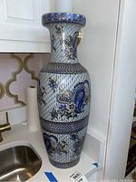 Photo of tall Chinese ceramic vase with blue and gold floral pattern near a kitchen sink.