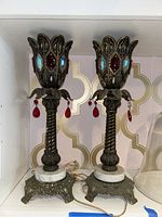 Pair of decorative brass torchiere lamps with marble bases and dangling crystal accents in red and blue.