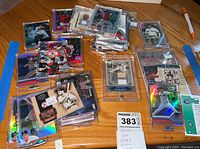 Photo of a collection of Boston Red Sox baseball cards, showing a variety of cards in plastic sleeves and protective cases on a wooden surface.