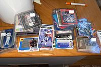 Overview of assorted sports trading cards including football, baseball, and hockey cards displayed on a table.