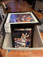 Plastic bin with multiple matted and framed sports prints, including visible Larry Bird and USA Basketball Team prints