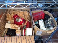 Photo of the open boxes containing multiple toy telephone collectibles including a red Mercury Glass telephone ornament, several toy telephones, and decorative telephone vehicles.