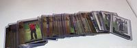 Fanned view of approximately 25 Tiger Woods trading cards in protective cases on a white surface