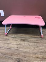 Side view showing foldable legs and the pink ergonomic surface with a cup holder on front right corner.