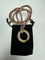 Full view of braided leather chain with large semi-precious stone circular pendant laid on black pouch