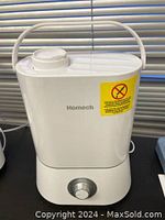 Front view of white Homech humidifier model HM-AH001 showing brand name, rotary mist output knob and yellow warning sticker.