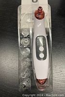 Handheld blackhead removal device in white with rose gold accents, six clear nozzle tips in plastic packaging, digital display with two buttons visible