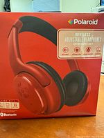Front box view of Polaroid wireless adjustable headphones in red, showing product image and brand name.