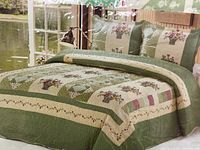 Image showing the quilt cover made and laid out on a bed, displaying the floral bouquet and patchwork pattern in green and cream tones.