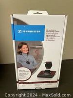 Front of product box showing brand, product image, and user wearing system near television.