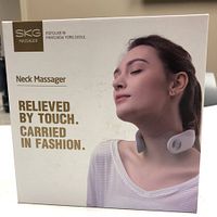 Front of the SKG Neck Massager retail box showing product image, model use, and tagline emphasizing portability and comfort.