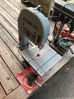 Front angled view of Delta bench band saw showing metal grated worktable, blade, and Delta logo on upper wheel cover.