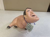 Side view of the ceramic bank showing the full body and face of the caricature figure.