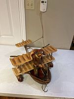 Photo showing the entire hanging flying machine model with tri-wing wooden textured wings and pilot figurine seated in cockpit