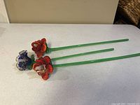 The three glass flowers arranged on a white surface showing stems and flower heads.