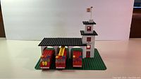 Front view of Lego Fire House with three fire trucks parked under black roof.