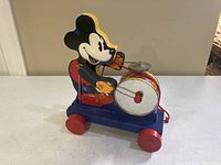 Front side view of the Mickey Mouse drummer wooden pull toy showing the character, drum, and cymbal clearly.