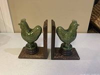 Full side view of the two ceramic roosters mounted on wood bookends showing overall size and wood finish.