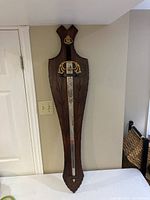 Full view of the sword mounted on the wooden plaque leaning against the wall showing overall condition and size.