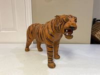 Full view of the tiger figurine on a white surface, showing its body and standing pose