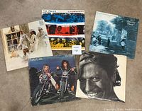 Five vinyl records displayed on the floor including titles by The Police, Moody Blues, Robert Palmer, and two Cheap Trick records.