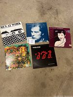 Full set of 5 vinyl records arranged on floor, showing all front album covers including Men At Work, Van Morrison, The Police, Duran Duran and an unidentified one