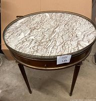Full view of the round bouillette table showing marble top, brass gallery, and mahogany wood legs.