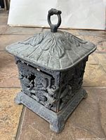 Side angle of cast iron lantern showing leaf-like top and loop handle